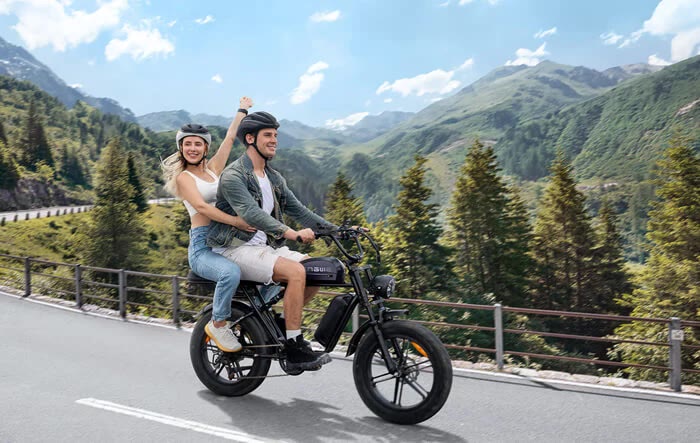 Two riders sharing a fat-tire electric bike on a mountain road